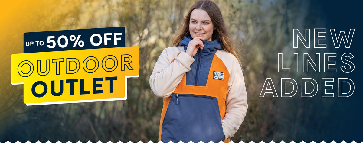 Outdoor jacket with orange and blue panels worn in a forest setting promoting up to 50% off outlet deals and new outdoor lines.