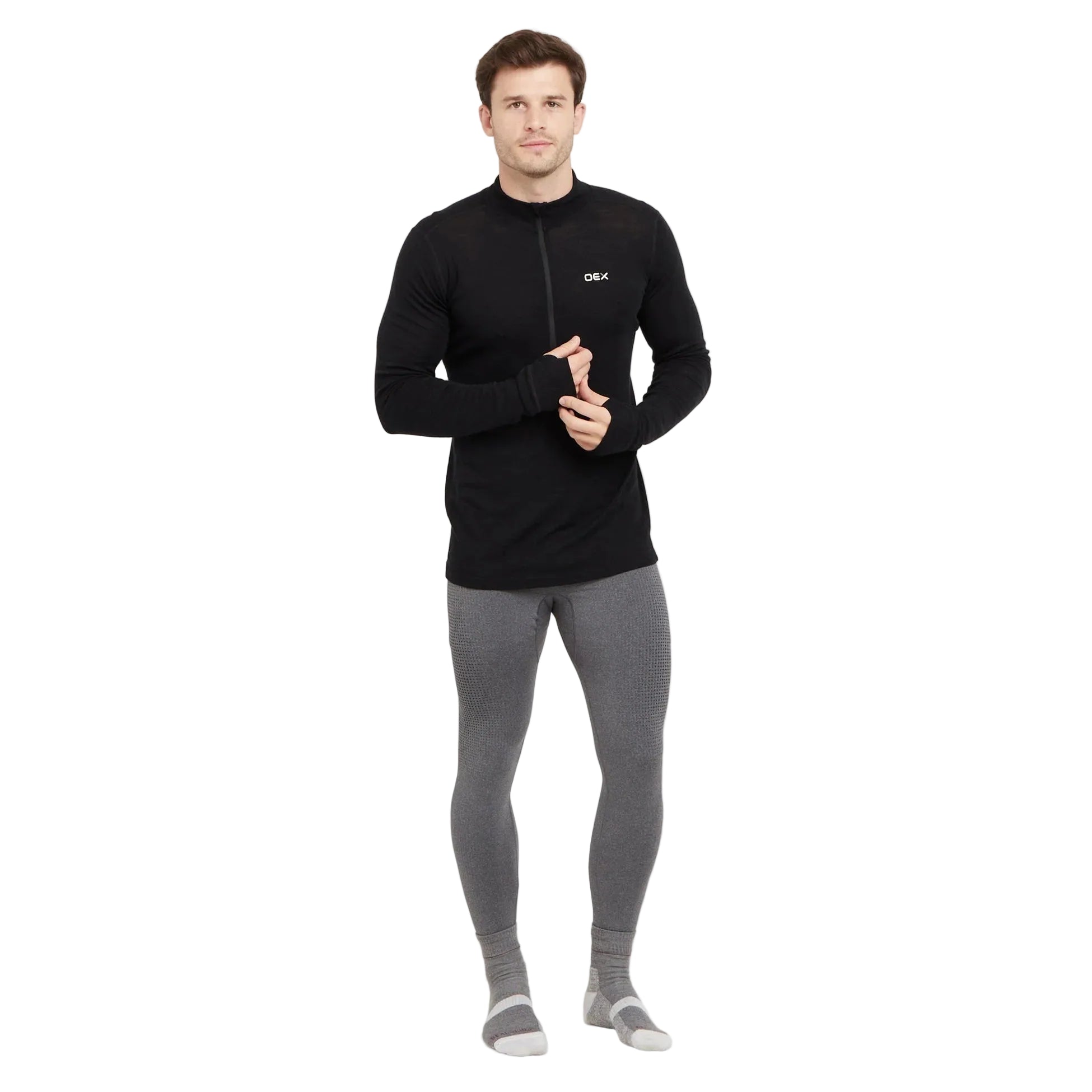 Man wearing a black long-sleeve top and gray leggings on a white background