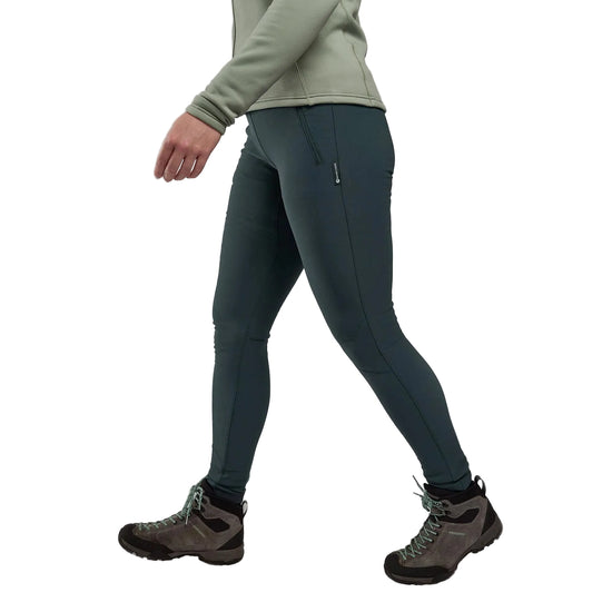 Person wearing dark green hiking pants and brown hiking boots on a light gray background
