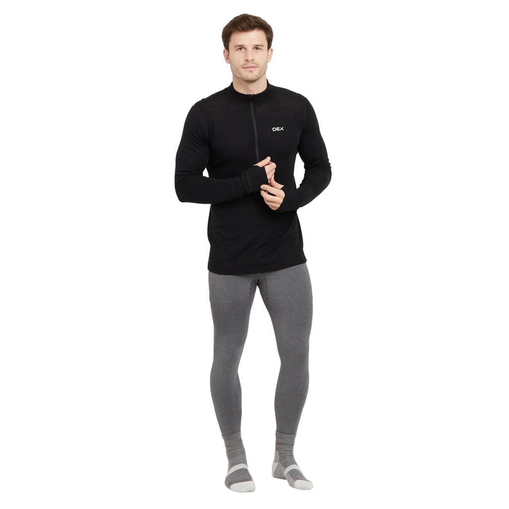 Man wearing a black long-sleeve top and gray leggings on a white background