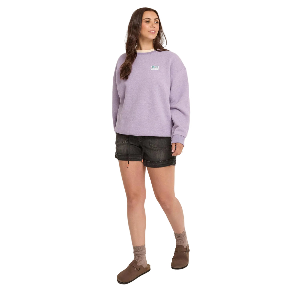 Woman wearing a light purple sweatshirt and black shorts against a white background