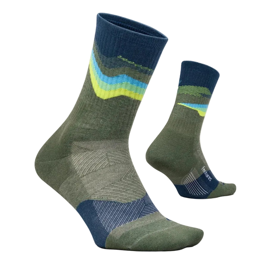 A pair of crew socks shown on invisible forms against a light off-white background. The socks feature a color-blocked design with a dark blue cuff, a green midsection, a blue heel, and a patterned upper section with wavy stripes of yellow, light blue, and green.