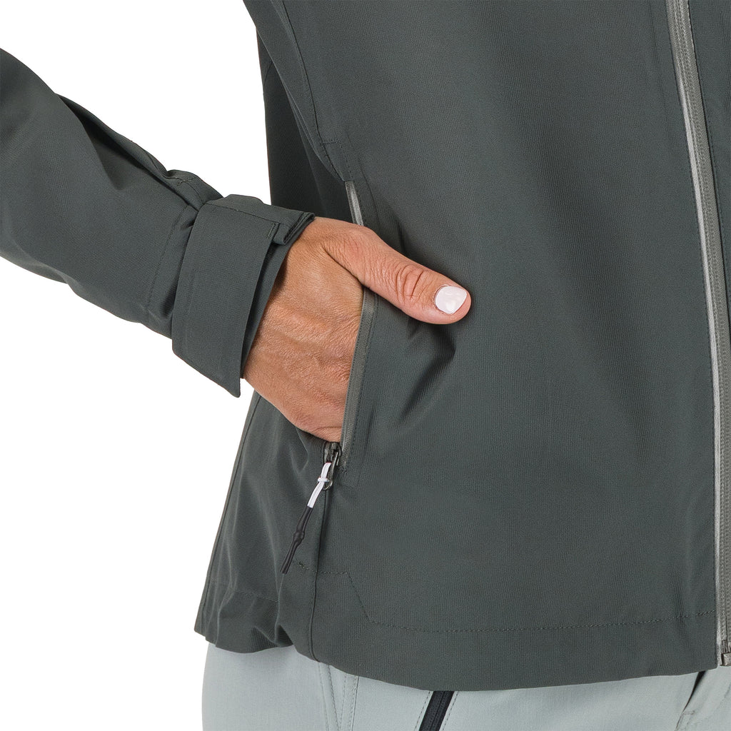 Person wearing a dark gray jacket with a hand in the pocket on a white background