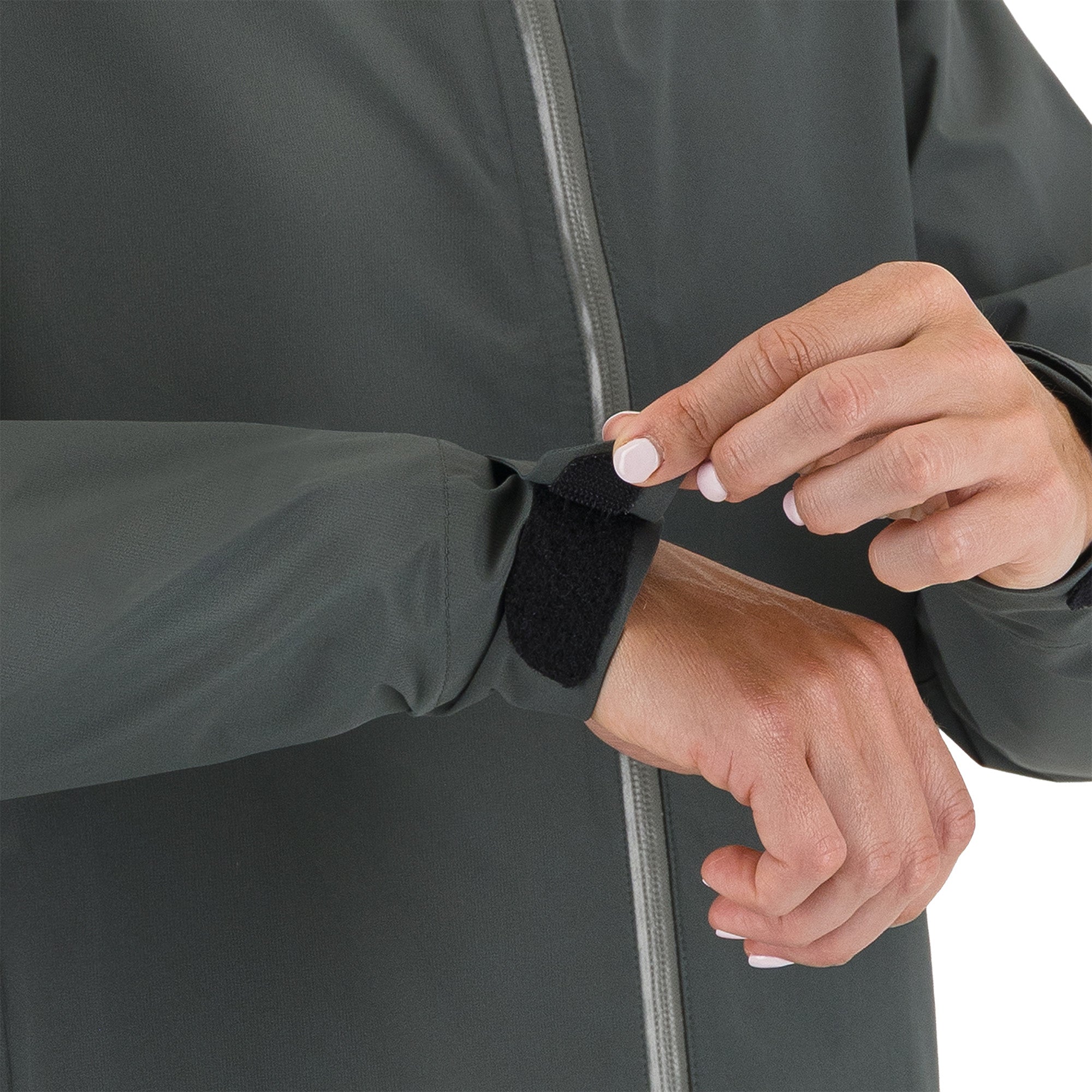 Person adjusting a black strap on a dark gray jacket against a white background