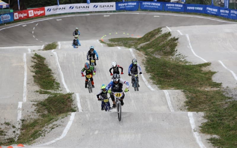 Group of BMX riders race each other on course