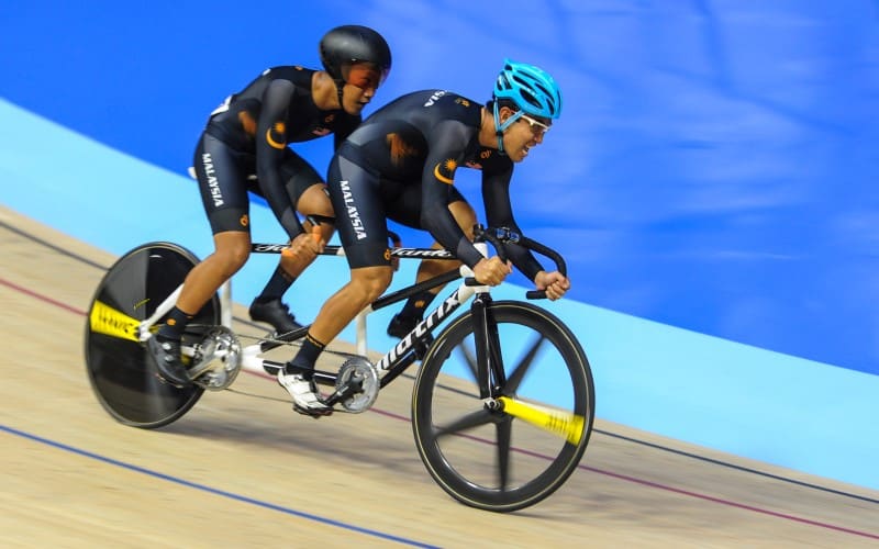 A para-cyclist and pilot on tandem compete on the track aboard a tandem bike